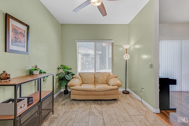 living area with a ceiling fan and baseboards