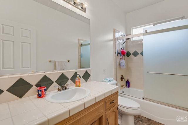 full bathroom featuring toilet, combined bath / shower with glass door, and vanity