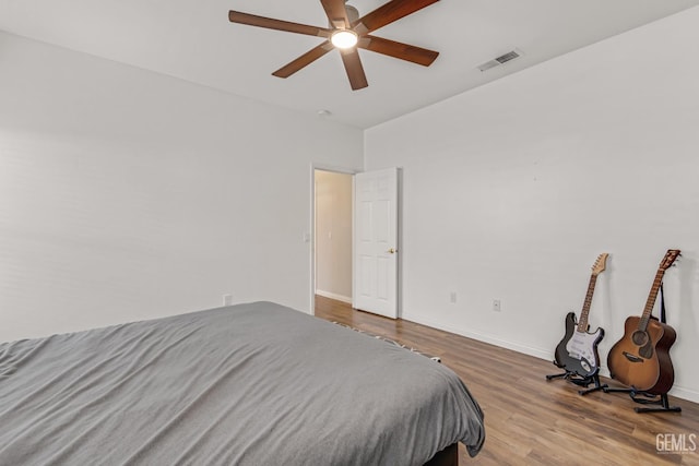 bedroom featuring light wood-style floors, baseboards, visible vents, and a ceiling fan