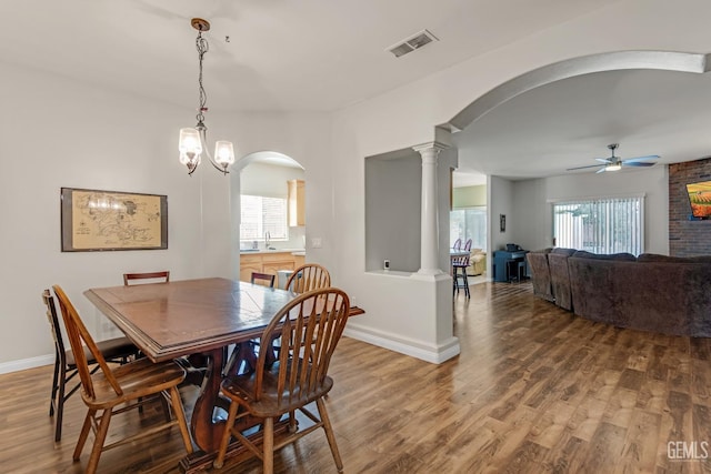 dining space with decorative columns, visible vents, arched walkways, and wood finished floors