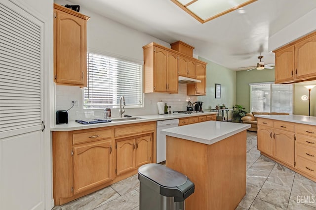 kitchen with dishwasher, a center island, light countertops, under cabinet range hood, and a sink