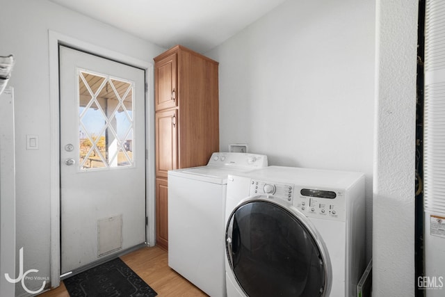 washroom featuring cabinets, light wood-type flooring, and washing machine and clothes dryer