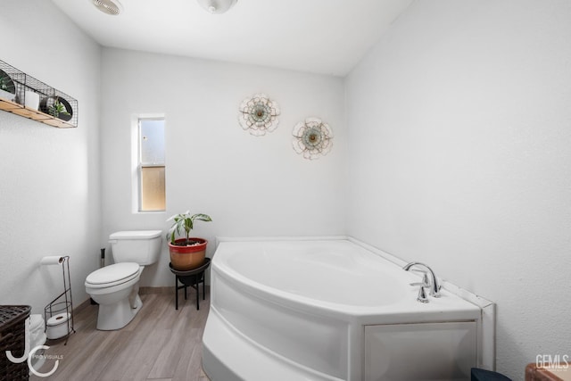 bathroom with hardwood / wood-style floors, toilet, and a tub