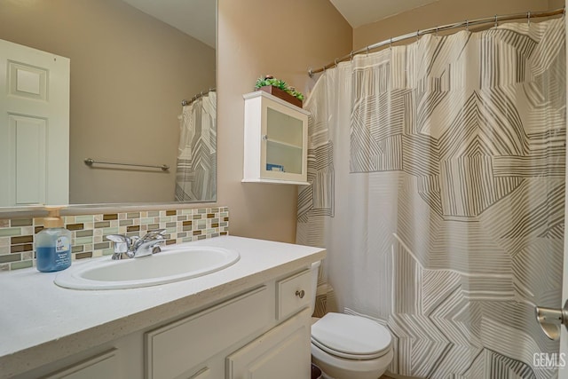 bathroom featuring vanity, toilet, and backsplash