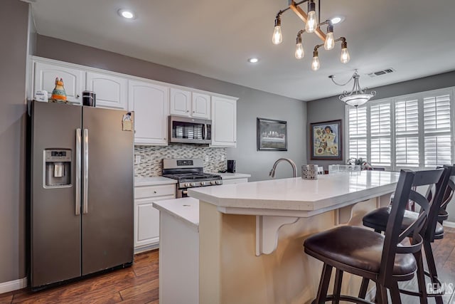 kitchen with white cabinetry, decorative light fixtures, appliances with stainless steel finishes, a kitchen island, and decorative backsplash