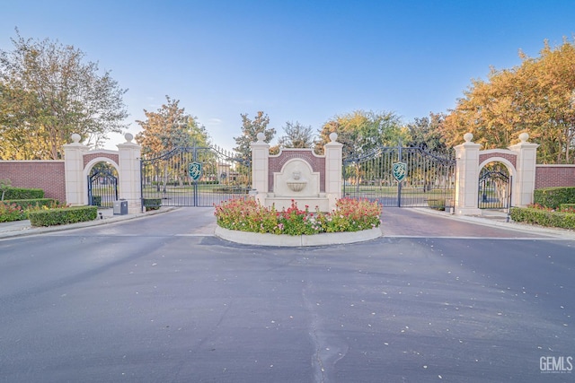 view of road with sidewalks, a gate, a gated entry, and curbs