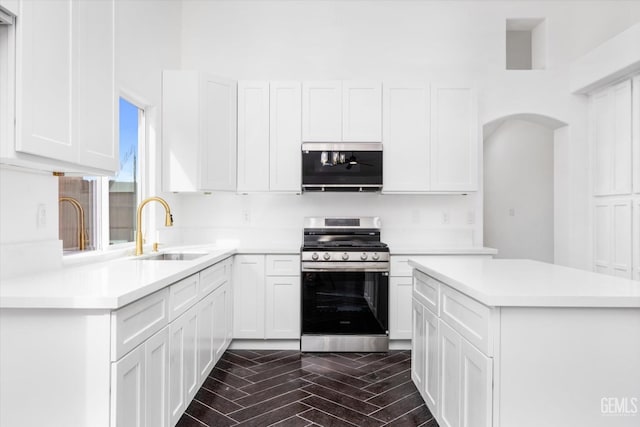 kitchen with white cabinetry, stainless steel gas range oven, sink, and dark hardwood / wood-style floors