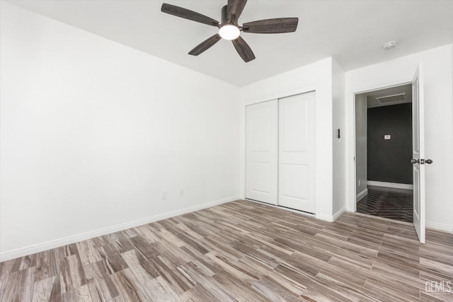 unfurnished bedroom featuring light hardwood / wood-style floors, a closet, and ceiling fan