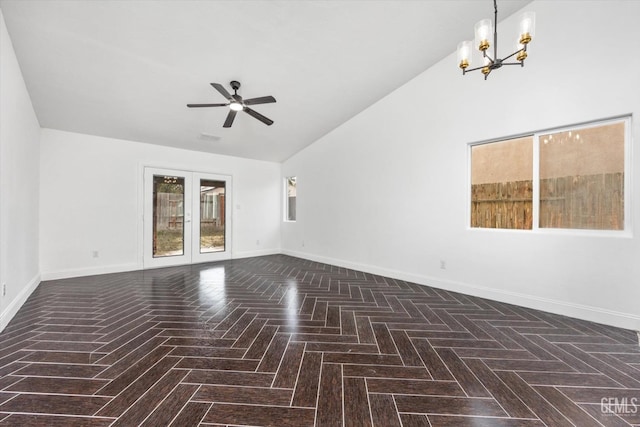 empty room with lofted ceiling, ceiling fan with notable chandelier, dark parquet floors, and french doors