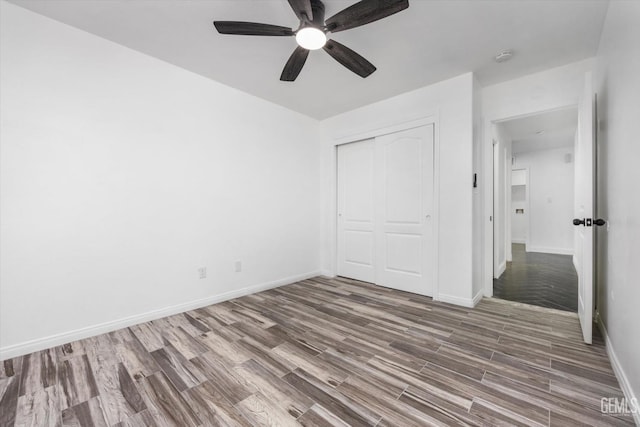 unfurnished bedroom featuring hardwood / wood-style floors, ceiling fan, and a closet