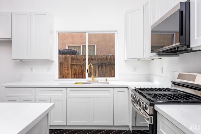 kitchen featuring sink, gas stove, and white cabinets