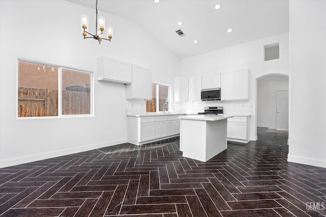 kitchen featuring white cabinetry, stainless steel appliances, a kitchen island, and hanging light fixtures