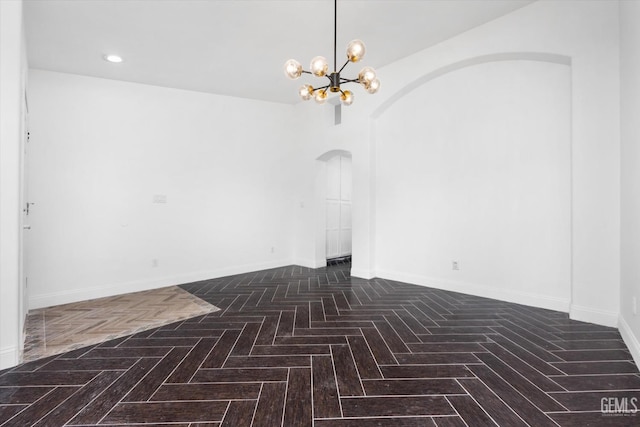 empty room featuring dark parquet floors and a chandelier