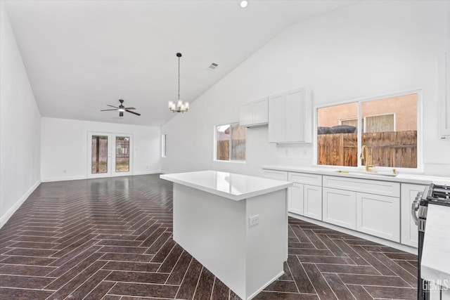 kitchen with sink, white cabinetry, high vaulted ceiling, stainless steel range with gas stovetop, and a kitchen island