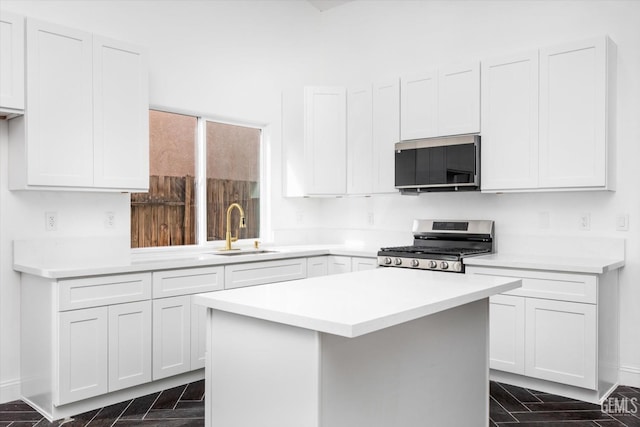 kitchen with stainless steel range, a center island, sink, and white cabinets