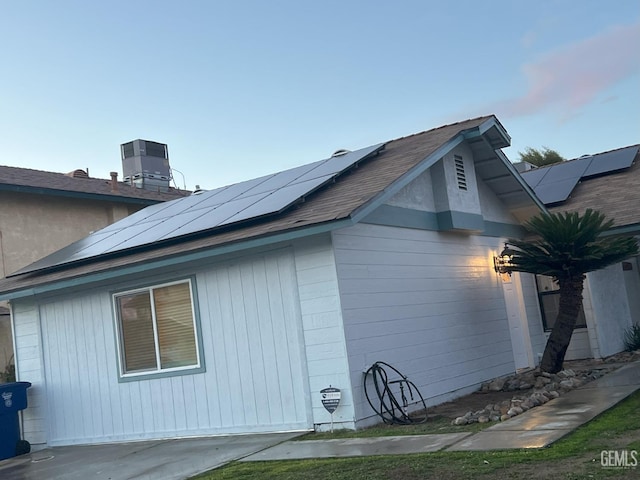 view of property exterior with cooling unit and roof mounted solar panels