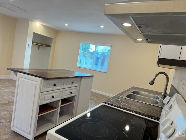 kitchen with dark countertops, white cabinets, a sink, and range with electric stovetop