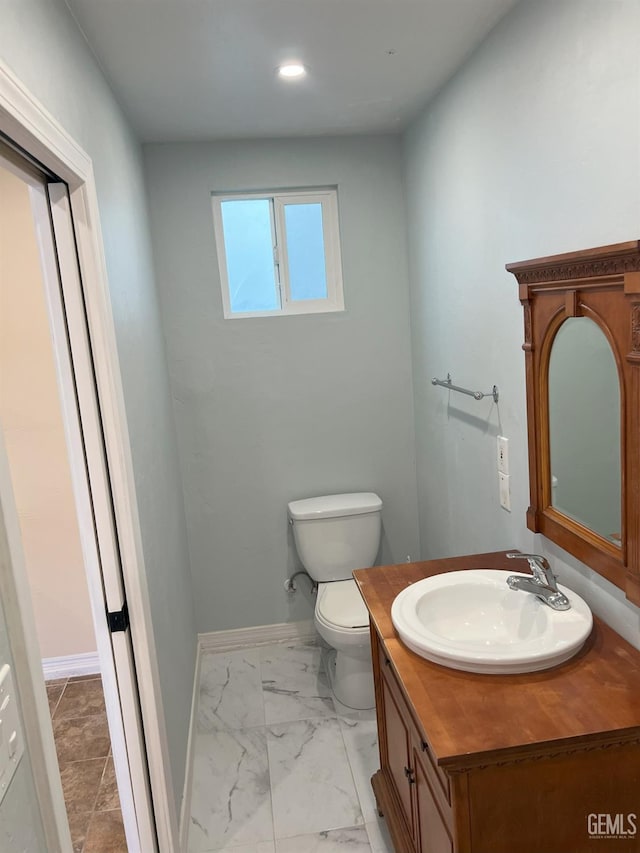 half bath featuring marble finish floor, recessed lighting, toilet, vanity, and baseboards