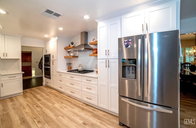 kitchen featuring stainless steel appliances, white cabinetry, and wall chimney exhaust hood