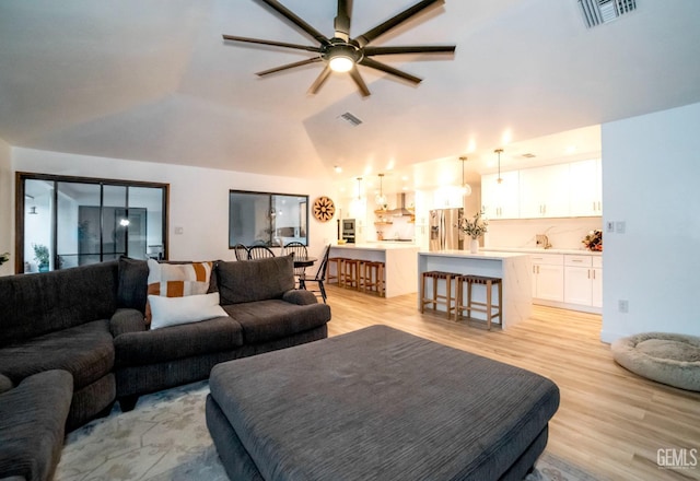 living room with light hardwood / wood-style flooring, ceiling fan, and lofted ceiling