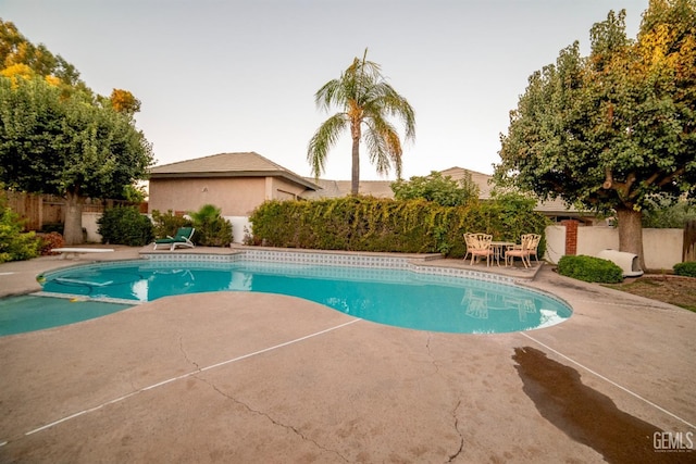 view of pool with a diving board and a patio