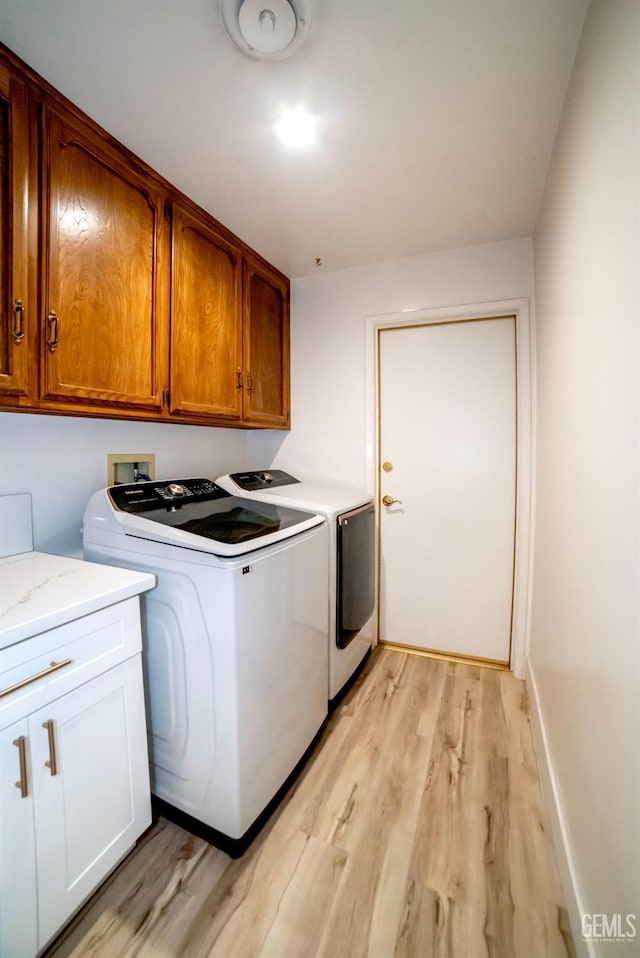 washroom with washer and dryer, light hardwood / wood-style flooring, and cabinets