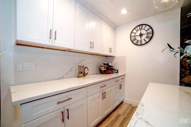 interior space with white cabinets, light hardwood / wood-style floors, and light stone counters