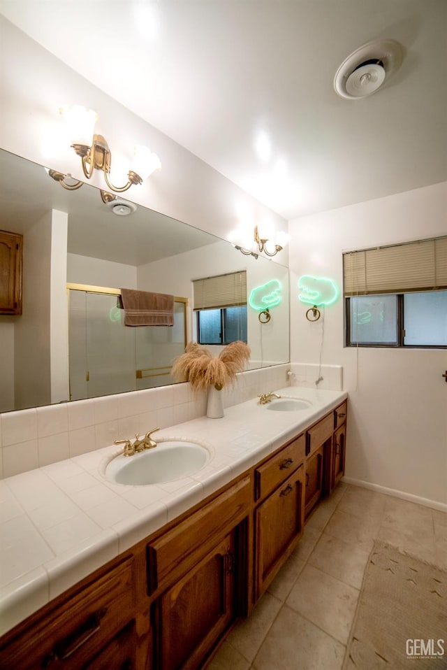 bathroom featuring tile patterned flooring, vanity, a shower with shower door, and an inviting chandelier