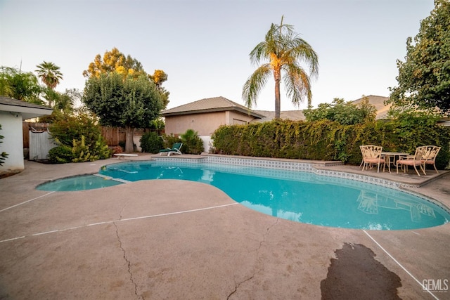 view of swimming pool featuring a patio and a diving board