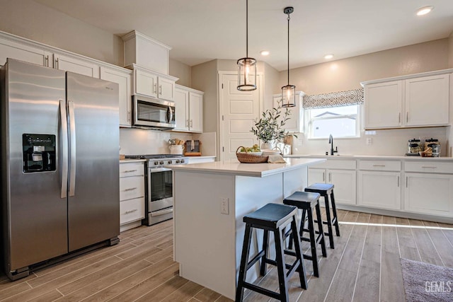 kitchen with decorative light fixtures, white cabinets, a kitchen bar, a center island, and stainless steel appliances