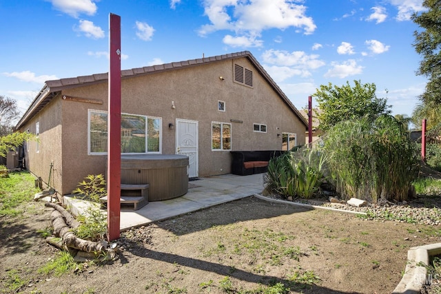 rear view of property featuring a hot tub and a patio