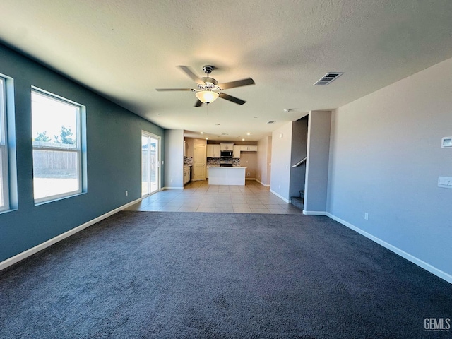5910 Bogart Dr, Bakersfield, CA 93313 - unfurnished living room featuring light carpet, ceiling fan, a textured ceiling, and light tile patterned floors
