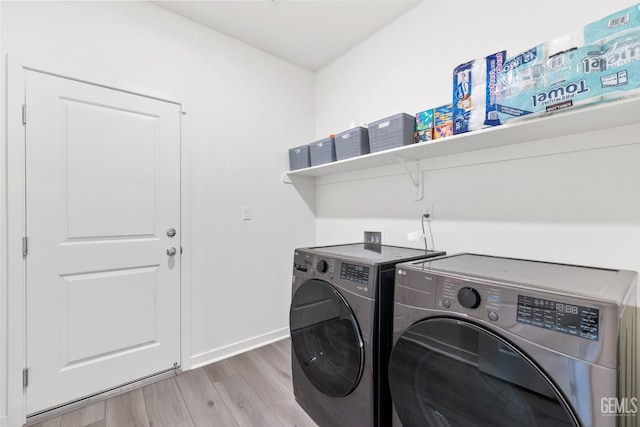 clothes washing area with baseboards, wood finished floors, washing machine and dryer, and laundry area