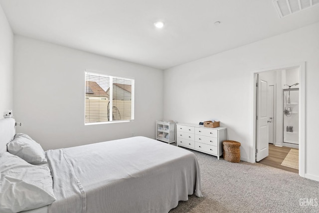 carpeted bedroom with ensuite bath, baseboards, and visible vents