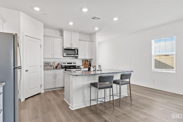 kitchen with visible vents, light wood-style flooring, appliances with stainless steel finishes, stone countertops, and white cabinetry