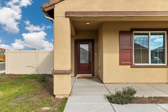 property entrance featuring fence and stucco siding