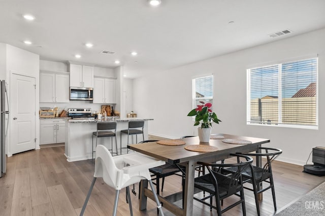 dining space featuring light wood finished floors, visible vents, recessed lighting, and baseboards