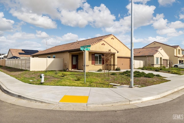 mediterranean / spanish home with stucco siding, driveway, a tile roof, fence, and a garage