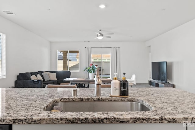 kitchen with a sink, light stone counters, and open floor plan