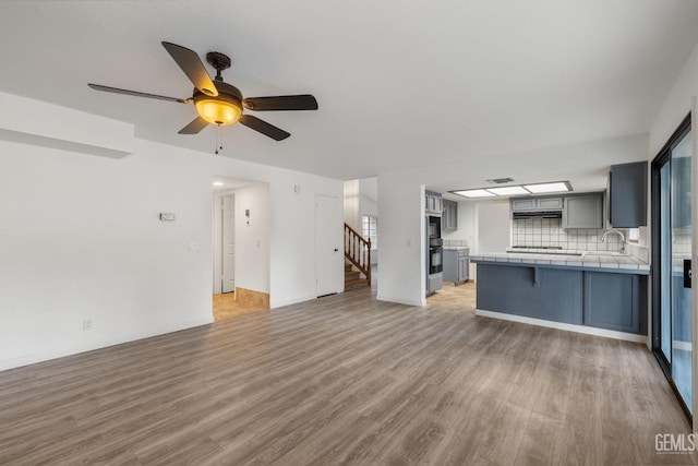 1224 N Mayflower Cir, Ridgecrest, CA 93555 - unfurnished living room with light wood finished floors, a sink, baseboards, ceiling fan, and stairs