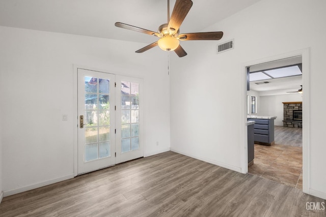 1224 N Mayflower Cir, Ridgecrest, CA 93555 - empty room with a fireplace, visible vents, baseboards, ceiling fan, and light wood-style floors
