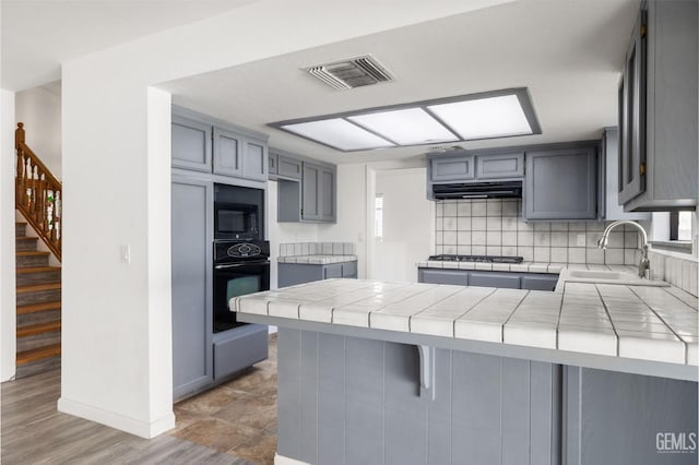 1224 N Mayflower Cir, Ridgecrest, CA 93555 - kitchen with under cabinet range hood, a sink, a peninsula, black appliances, and gray cabinets