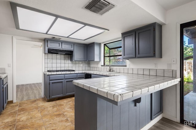 1224 N Mayflower Cir, Ridgecrest, CA 93555 - kitchen featuring a sink, a peninsula, visible vents, decorative backsplash, and gas stovetop