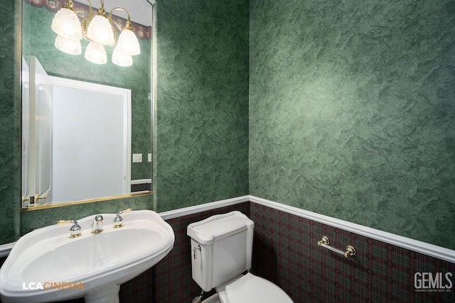 bathroom with sink, a notable chandelier, and toilet