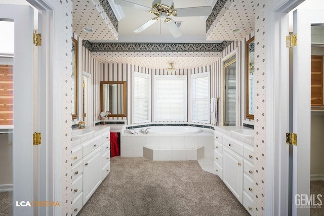 bathroom with tiled tub, vanity, and ceiling fan