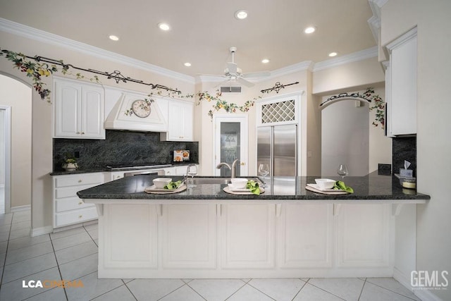 kitchen featuring premium range hood, sink, kitchen peninsula, stainless steel appliances, and white cabinets