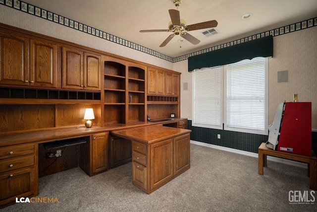 carpeted office with built in desk and ceiling fan