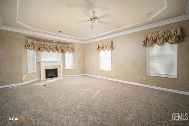 unfurnished living room with a tiled fireplace, crown molding, carpet floors, and ceiling fan