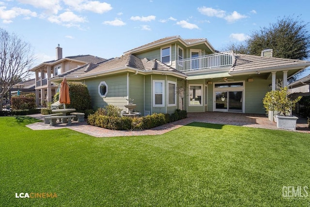 back of property featuring a patio, a balcony, ceiling fan, and a lawn