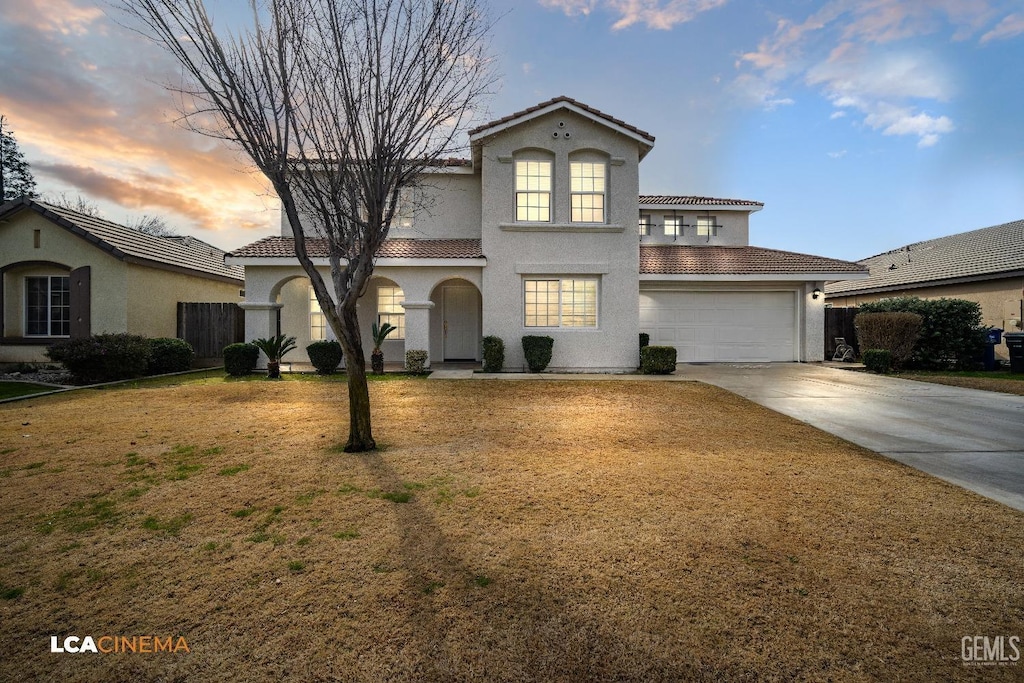 mediterranean / spanish-style house featuring a garage and a lawn